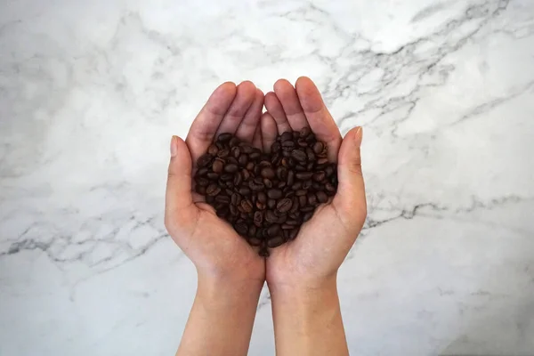 coffee beans in hands, heart shape, with marble background