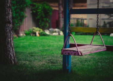 Bahçede yeşilliğin arka planında zincirli ahşap salıncak