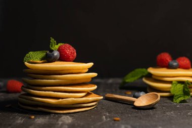 Koyu arkaplanda böğürtlenli krep (yaban mersini, ahududu) ve nane şekeri yığını..