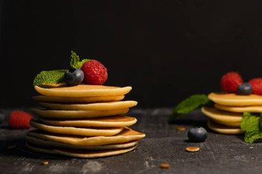 Koyu arkaplanda böğürtlenli krep (yaban mersini, ahududu) ve nane şekeri yığını..