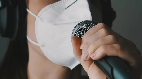 Jonge zangeres die zingt in de microfoon met gezichtsmasker in de thuisstudio. Werk op afstand, zelfontbinding en preventie van verspreiding van het coronavirus — Stockfoto