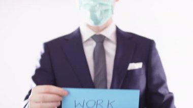 Uzaktan çalış. Tıbbi maskeli bir iş adamı evden çalışmasını tavsiye ediyor.