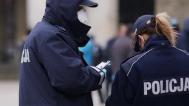 Varşova, Polonya 04.15.2020 - Girişimcilerin protestosu, sokağa çıkma yasağı sırasında kadın ve erkek polis memurları kalabalığın önünde. Polis para cezası yazıyor.
