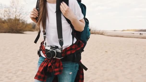 Młoda kobieta fotograf i poszukiwacz przygód spaceruje po piaszczystej plaży w zwolnionym tempie. — Wideo stockowe