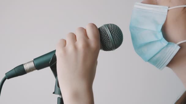Junge Sängerin singt in Mikrofon und Mundschutz im heimischen Studio. Fernarbeit, Selbstisolierung und Verhinderung der Ausbreitung des Coronavirus — Stockvideo