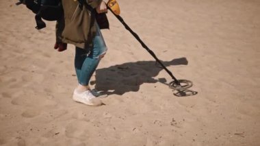 Metal dedektörle kumu tarayıp kayıp değerli metalleri bulan tanınmamış bir insan..