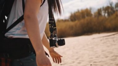 Yaklaş, sırt çantalı kadın, kameralı gezgin kumsalda yürüyor. Macera ve keşif kavramı