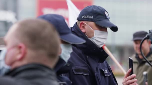 Warszawa, Polska 04.15.2020 - Protest Przedsiębiorców, Młody Policjant z maską ochronną w tłumie ludzi w środku godziny policyjnej — Wideo stockowe