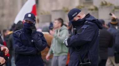 Varşova, Polonya 04.15.2020 - Girişimcilerin protestosu, sokağa çıkma yasağı sırasında kadın ve erkek polis memurları kalabalığın önünde. Polis para cezası yazıyor.