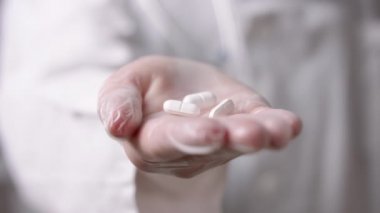 Yaklaş, doktor elinde eldivenle beyaz haplar tutuyor. Grip için ilaç ve tedavi