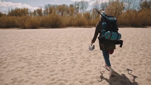 Explorer με το σακίδιο πλάτης, το παπούτσι και τον μεταλλικό ανιχνευτή περπατώντας στην αμμώδη παραλία. ψάχνοντας για το θησαυρό — Αρχείο Βίντεο