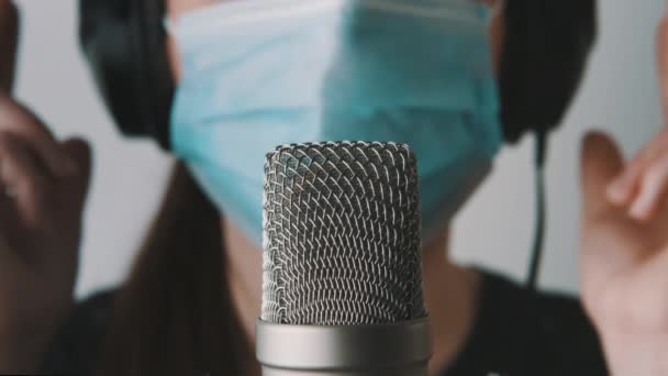 Junge Journalistin mit medizinischer Maske und Mikrofon, die im Studio arbeitet. Nahaufnahme — Stockvideo