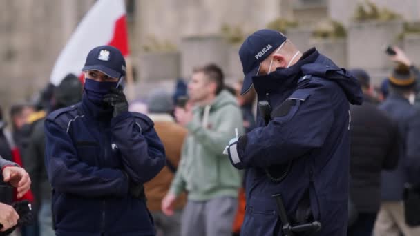 Varșovia, Polonia 04.15.2020 - Protestul antreprenorilor, ofițerilor de poliție femeie și bărbat în fața mulțimii de oameni în timpul stingerii stingerii. Polițist scris amenzi — Videoclip de stoc