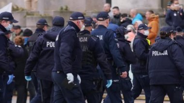 Varşova, Polonya 04.15.2020 - Girişimcilerin protestosu, sokağa çıkma yasağı saatlerinde Varşova 'da yüzleri maskeli birçok polis memuru