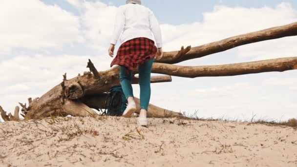 Νεαρή ανέμελη γυναίκα περπατά στην άμμο και παίρνει το σακίδιό της. αργή κίνηση χαμηλή γωνία shot — Αρχείο Βίντεο