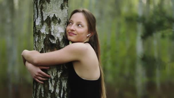 Mladá šťastná běloška objímající strom v lese. — Stock video