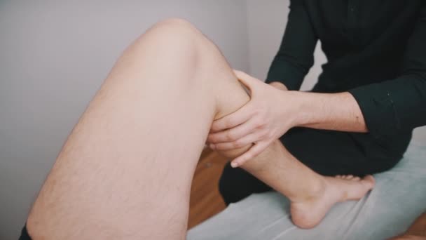Masaje médico en la pierna en un centro de fisioterapia. Concepto de asistencia sanitaria y recuperación — Vídeos de Stock