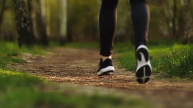 Ormanda spor ayakkabılarla koşan kadın bacakları yakın mesafede. Ormanda ağır çekimde koşan kadın.