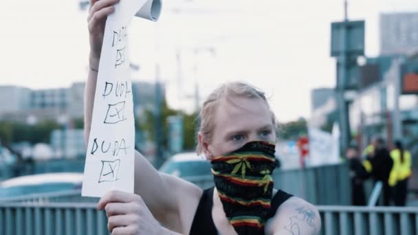 ワルシャワ、ポーランド、 05.07.2020 。-起業家の抗議。彼の顔にスカーフを持つ男はそれに現在のポリッシュ社長の名前を持つトイレットペーパーを保持しています — ストック動画