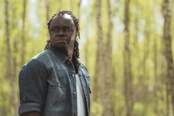 Portret van een Afrikaanse man in het bos die over de schouder kijkt. Kopieerruimte — Stockfoto