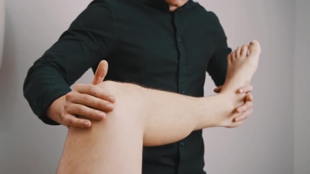 Fysiotherapie. Technicus inspecteert de knieflexibiliteit — Stockvideo