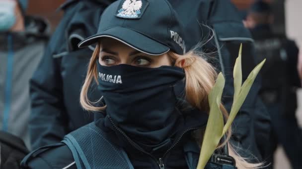ワルシャワ、ポーランド05.16.2020 。-起業家の抗議。制服と顔の保護にチューリップを持つ女性警察官の肖像 — ストック動画