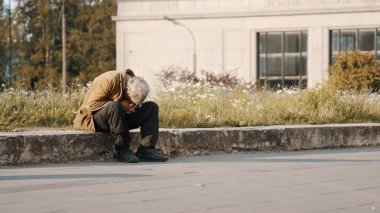 Varşova, Polonya 05.16.2020. - Umutsuz ve evsiz bir adam eğilmiş kafasıyla sokakta oturuyor.