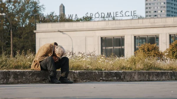 Varşova, Polonya 05.16.2020. - Umutsuz ve evsiz bir adam eğilmiş kafasıyla sokakta oturuyor. — Stok fotoğraf