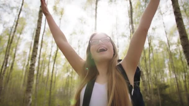 Mujer joven con mochila, viajero levantando las manos en el bosque disfrutando de la libertad y las vacaciones — Vídeo de stock
