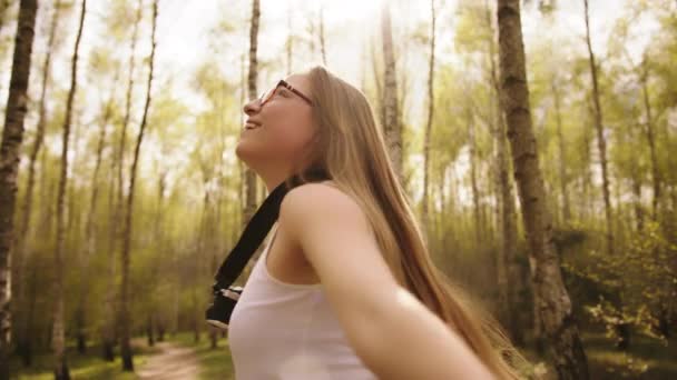 Genç beyaz kadın turist boynunda antika kamerayla ormanda dönüyor. Tatil özgürlüğünün tadını çıkarıyorum. — Stok video
