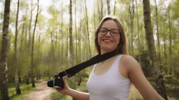 Joven mujer caucásica turista girando en el bosque con cámara vintage alrededor de su cuello. Disfrutar de vacaciones concepto de libertad — Vídeo de stock
