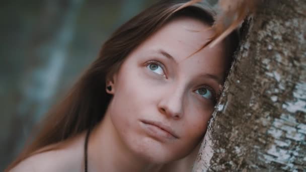 Porträt einer schönen jungen Frau, die sich mit Traumfänger an den Baum lehnt — Stockvideo