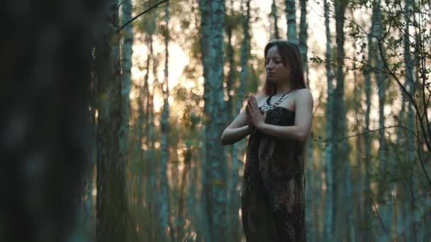 Mujer caucásica joven practica yoga o meditación en el bosque. Conexión con la naturaleza — Vídeo de stock