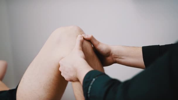 Terapeut kontroluje pružnost kolene. Koncept sportovní fyzioterapie — Stock video
