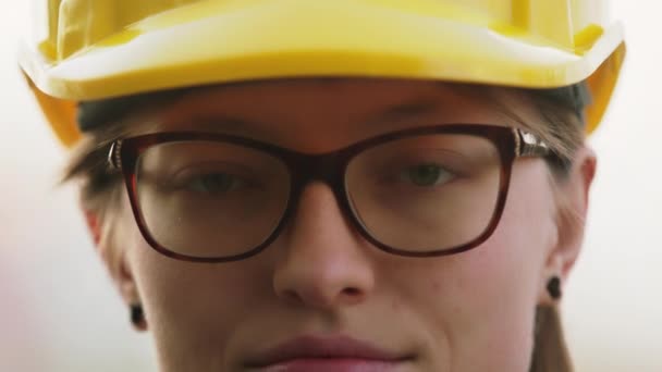 Sluit maar af. Jonge vrouw, ingenieur met gele harde hoed. Portret, slow motion met ondiepe scherptediepte — Stockvideo