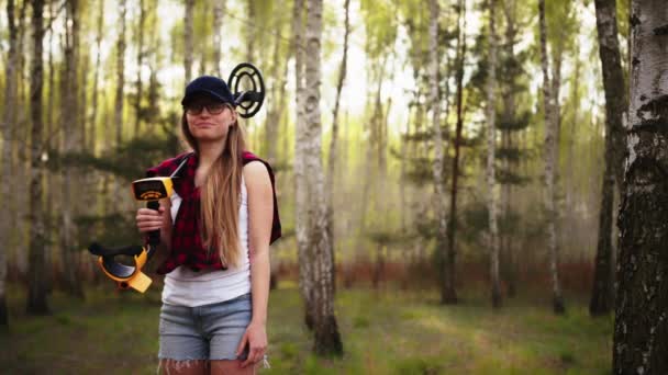 Fiatal női felfedező az erdőben, fémdetektorral a sarkán. Teljes felvétel fénymásolási hellyel — Stock videók