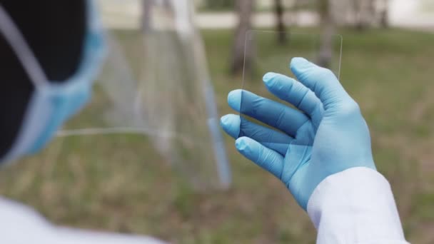 Mann mit Gesichtsschutz und medizinischen Masken, Glas wie einen virtuellen Bildschirm haltend. Pandemiekonzept. Bildschirmwechsel — Stockvideo