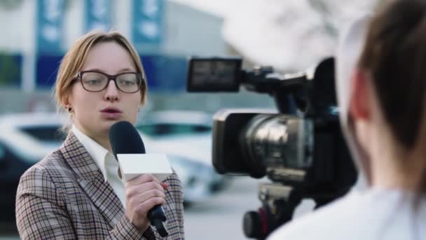 Mujer joven da una entrevista en la calle. Periodista reportando en la calle — Vídeo de stock