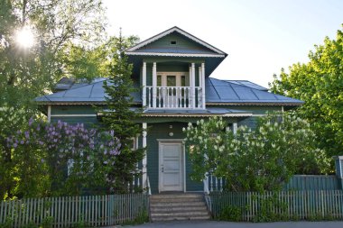 Ahşap ev ve batan güneşin ışınlarında açan leylak. Vologda, Rusya