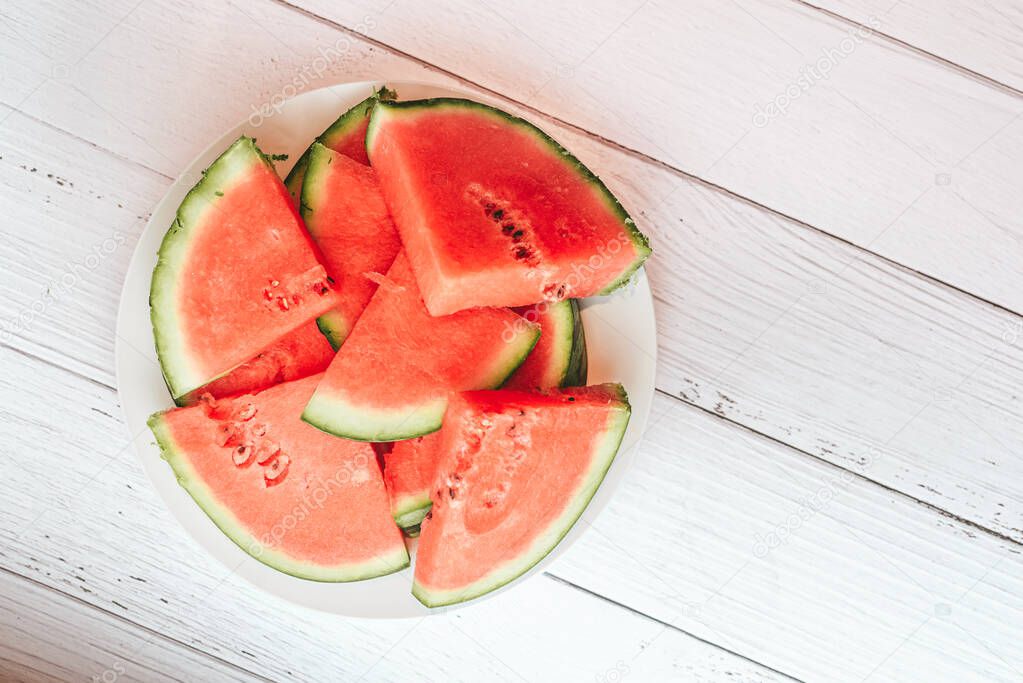 Pieces of fresh red watermelon on a clean white wooden table