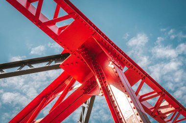 Mavi gökyüzündeki vidalarla sıkıca bağlanmış çelik sütunlar güçlü bir bağı sembolize eder.