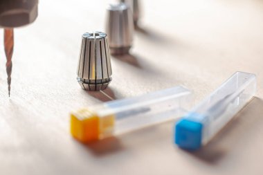 Cnc makinesinde üç kolej, kutularda iki değirmen kesicisi, ahşap bir yüzey üzerinde bir değirmen makası ile bir değirmen makası