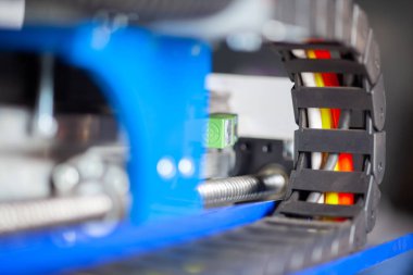 Siyahlı CNC makinesinin kablo rehberleri. Arka planda top vida vagonu var.