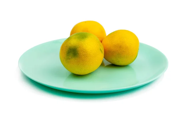 三颗黄绿色的柚子躺在一个蓝绿色圆盘上 背景是白色的 隔离的 — 图库照片