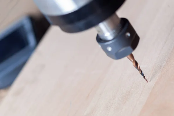 the spindle of the milling machine with the milling cutter is located above the wooden workpiece