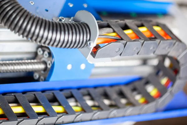 Siyahlı CNC makinesinin kablo rehberleri. Arka planda top vida vagonu var.