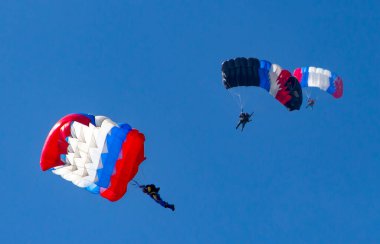 Mavi gökyüzüne karşı üç paraşütçü
