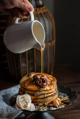 Mutfağın karanlık arka planında beyaz bir sürahide bal akan leziz gözlemeler. Güzel bayana kahvaltı.