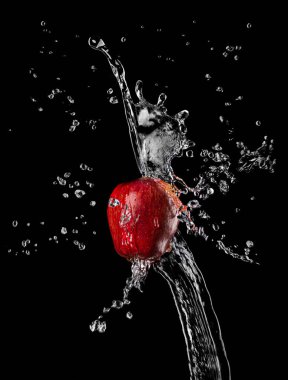 Kırmızı elma, siyah arka planda, su püskürtüsünde.