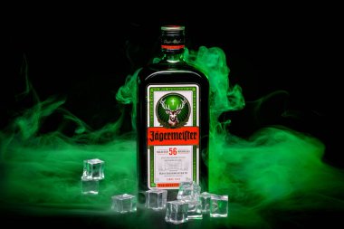 Rostov, Rusya, Temmuz 2019. .Bir şişe Jagermeister, 56 bitki ve baharattan yapılmış bir Alman sindirimi, Mast-Jagermeister SE 'nin ana ürünü, buz küpleri ve yeşil dumanla siyah bir arka planda. Sadece editör kullanımı